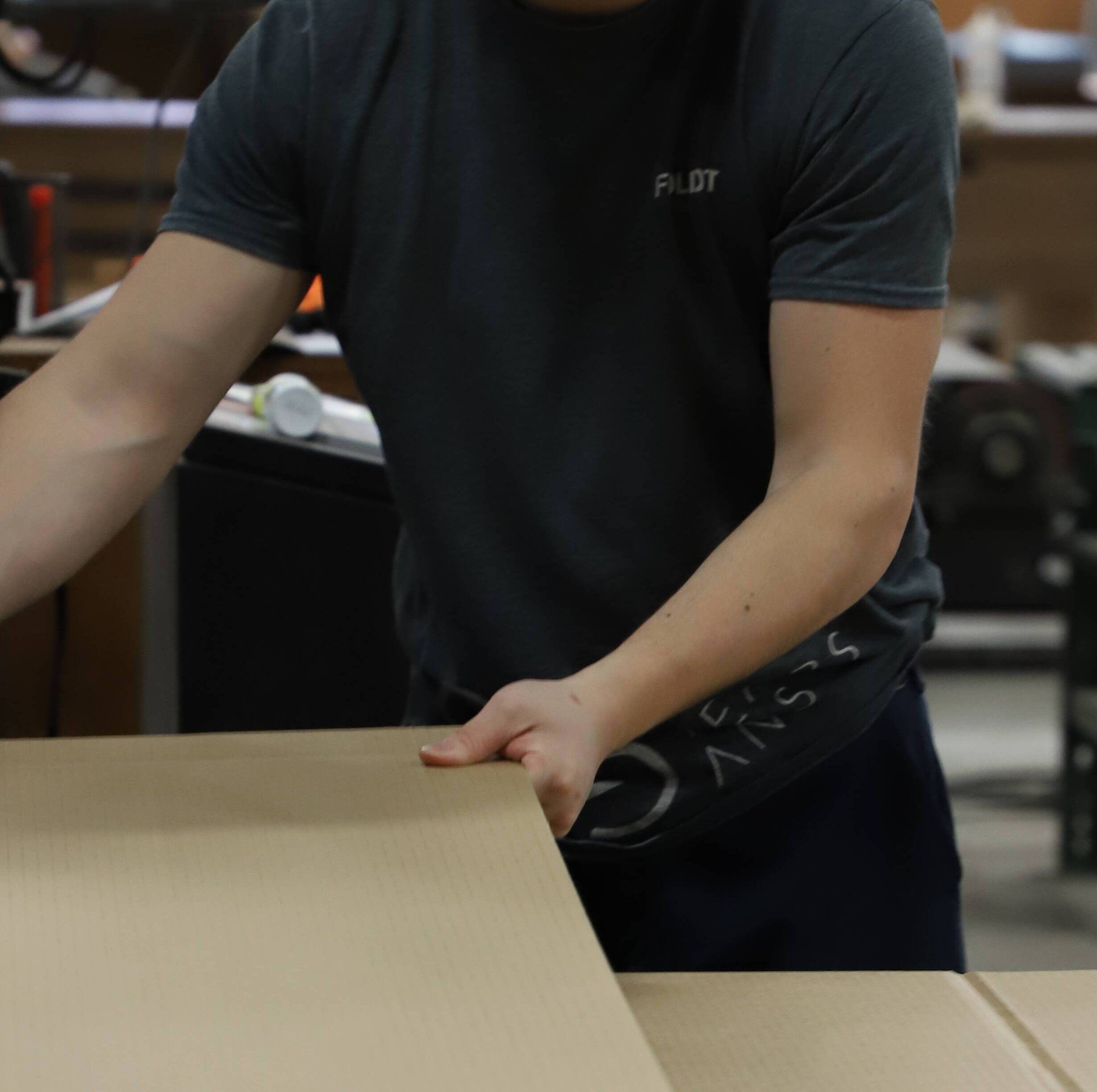 Foliot worker handling recycled cardboard boxes manufactured in-house.